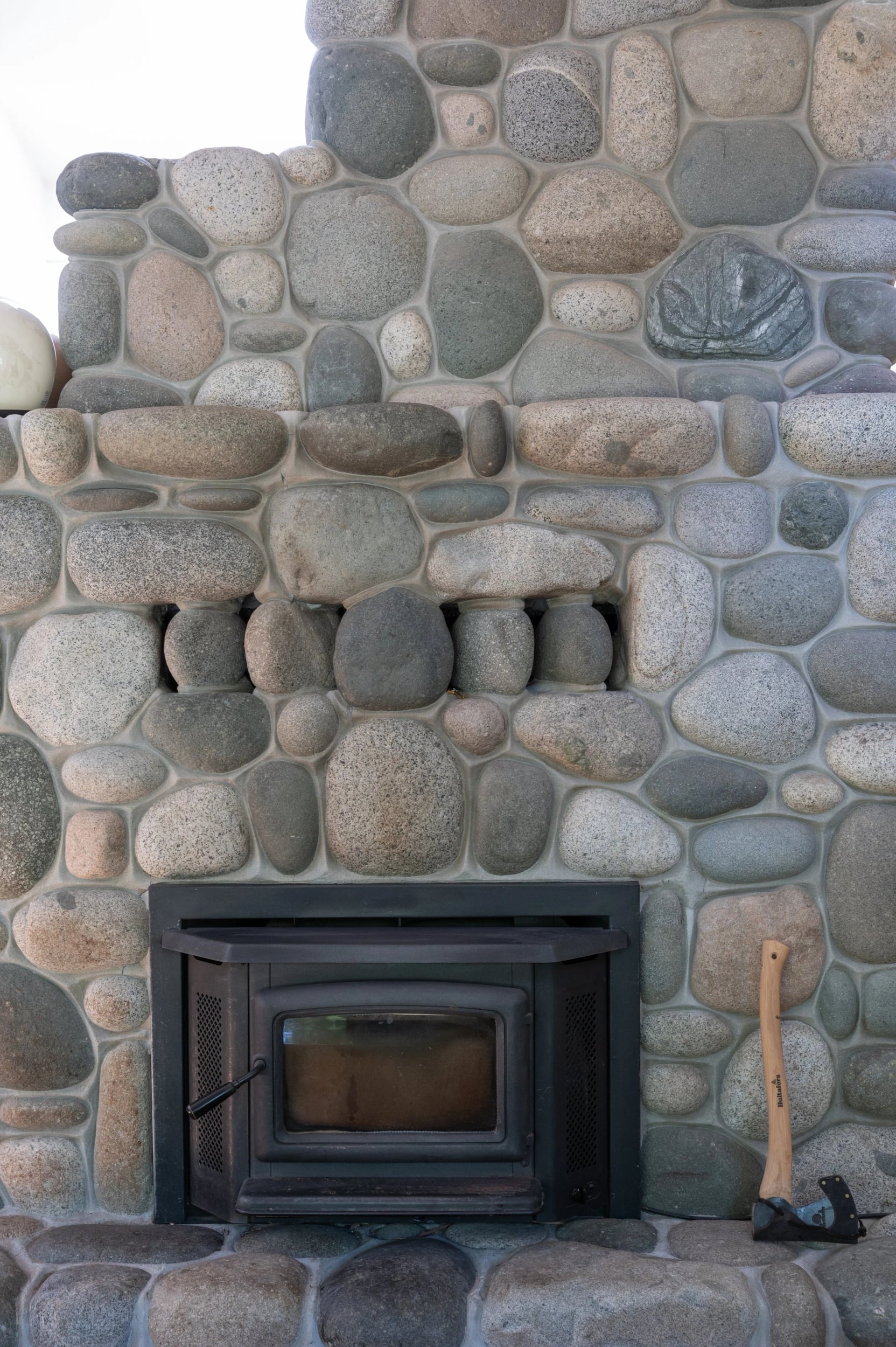 A river-stone fireplace with a black insert
