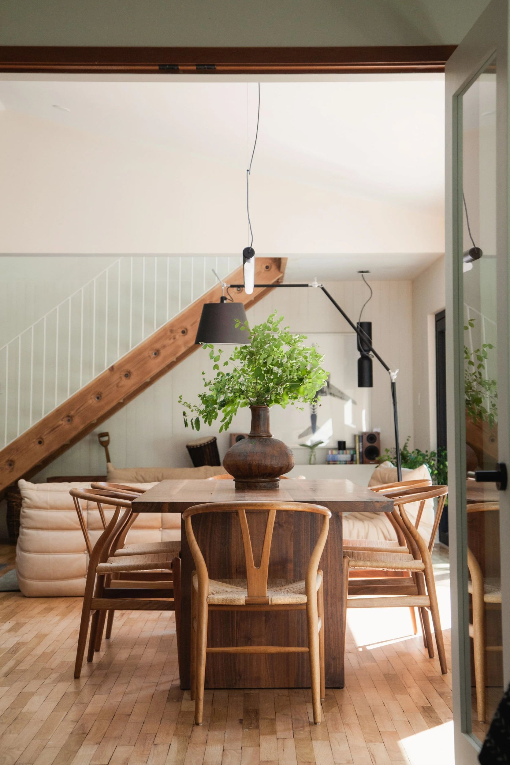 A round table and wooden chairs beneath a pendant lamp