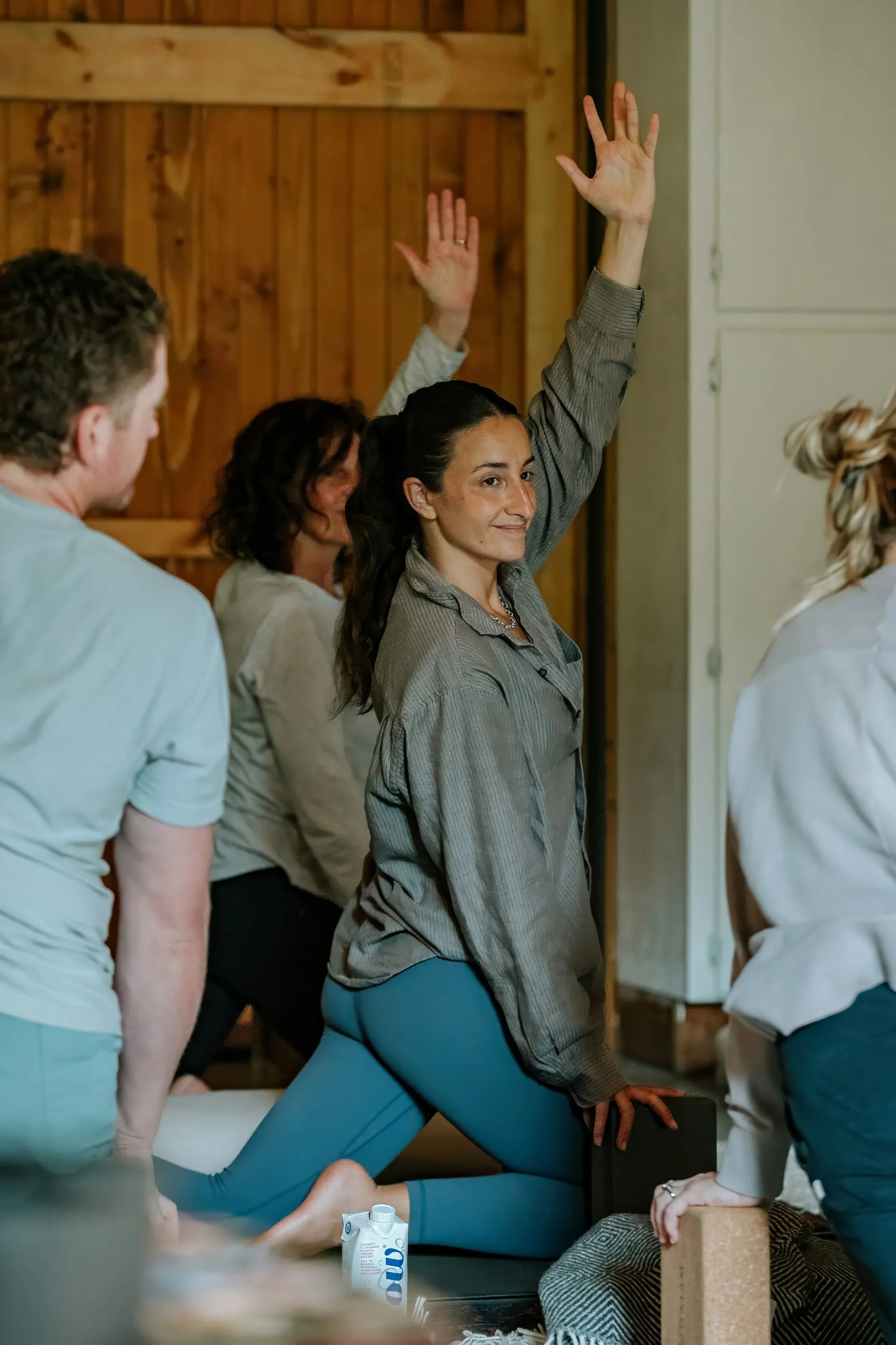 A woman smiling mid-stretch during a yoga class