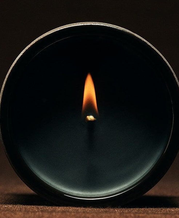 A lit Ceremonial Candle in a black glass vessel, seen face on
